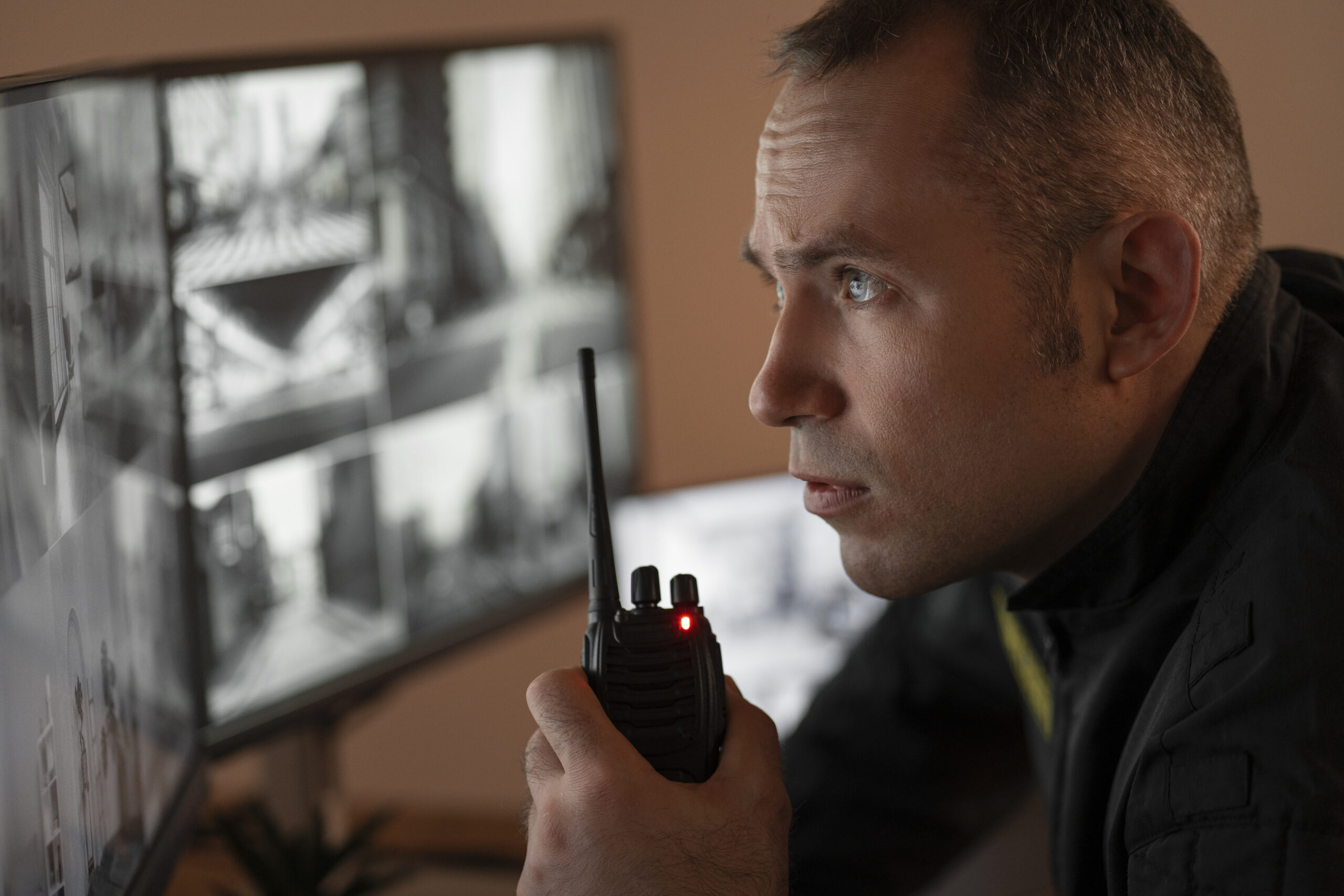 portrait-male-security-guard-with-radio-station-camera-screens